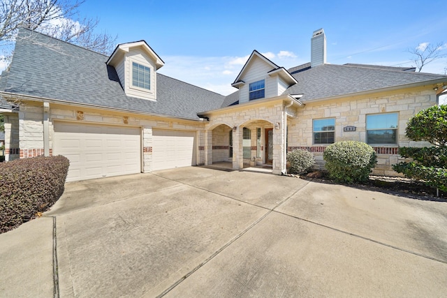 view of front of property featuring a shingled roof, concrete driveway, stone siding, and an attached garage