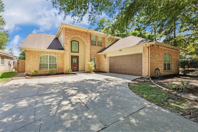 view of front facade featuring brick siding, roof with shingles, an attached garage, fence, and driveway