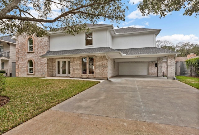 view of front facade featuring a front yard, french doors, brick siding, and driveway