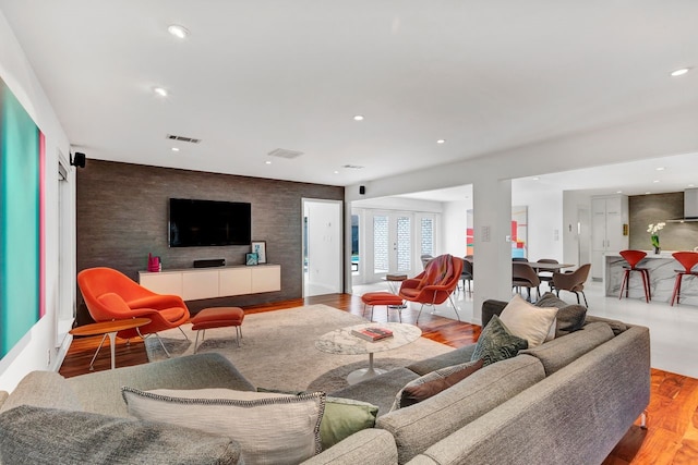 living area featuring an accent wall, visible vents, wood finished floors, and recessed lighting