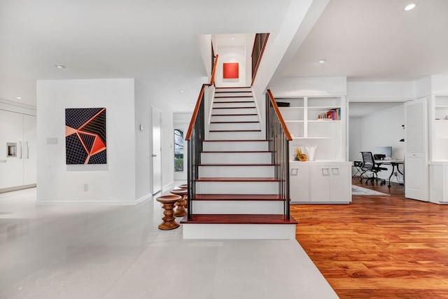 stairway with baseboards, wood finished floors, and recessed lighting