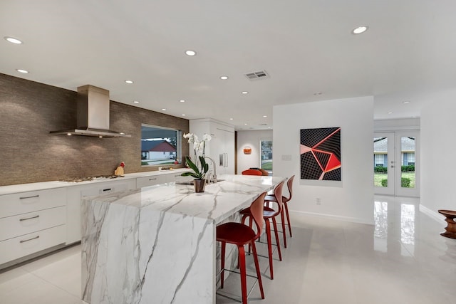 kitchen featuring wall chimney range hood, white cabinetry, modern cabinets, and visible vents