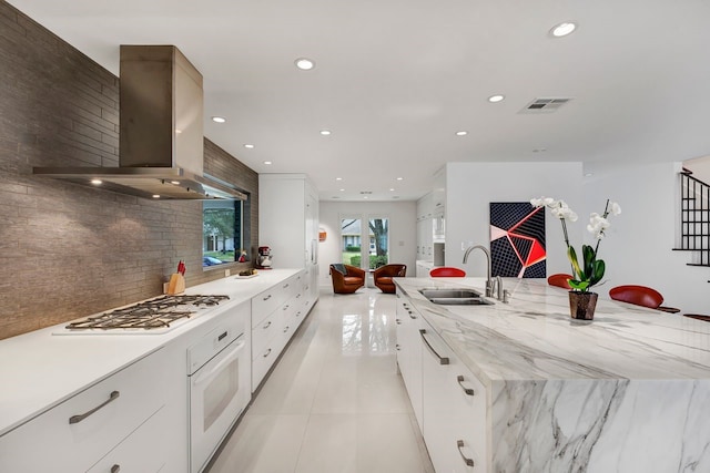 kitchen with white appliances, a sink, visible vents, a large island, and island exhaust hood