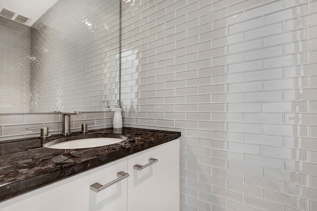 bathroom with tasteful backsplash, visible vents, tile walls, and vanity