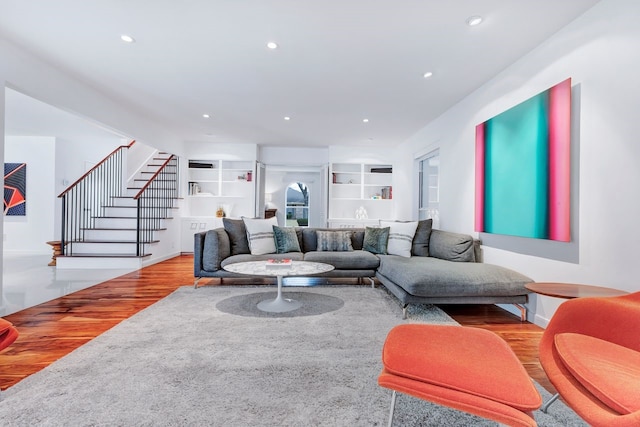 living area with stairs, recessed lighting, built in shelves, and wood finished floors