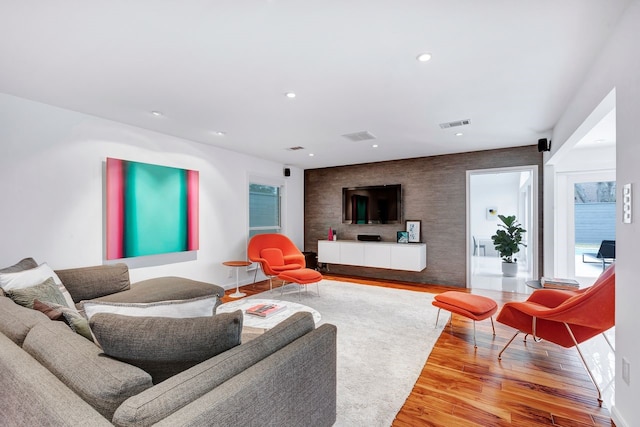 living area with recessed lighting, an accent wall, wood finished floors, visible vents, and baseboards