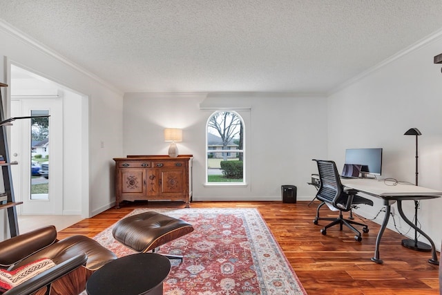 home office with a textured ceiling, ornamental molding, wood finished floors, and baseboards