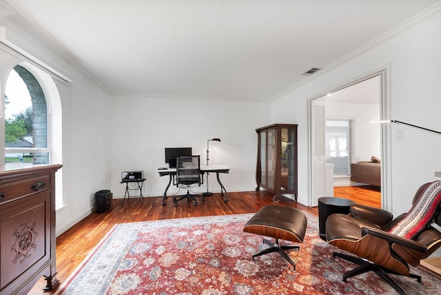 home office featuring ornamental molding, light wood finished floors, a textured ceiling, and visible vents