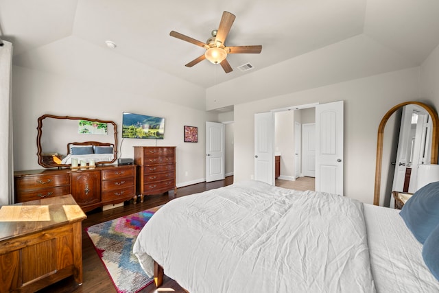 bedroom featuring dark wood finished floors, visible vents, a ceiling fan, vaulted ceiling, and baseboards