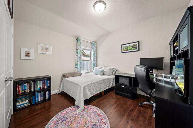 bedroom with a textured ceiling, dark wood-type flooring, and baseboards