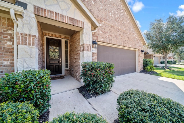 entrance to property with an attached garage, concrete driveway, and brick siding