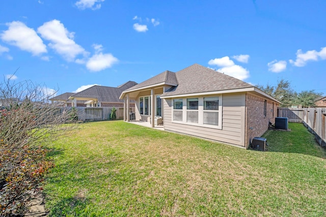 back of house featuring central AC unit, a fenced backyard, brick siding, roof with shingles, and a lawn