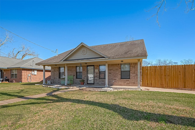 bungalow with brick siding, roof with shingles, covered porch, a front yard, and fence