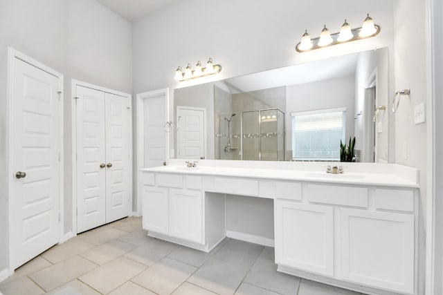 bathroom with double vanity, a stall shower, a closet, tile patterned flooring, and a sink