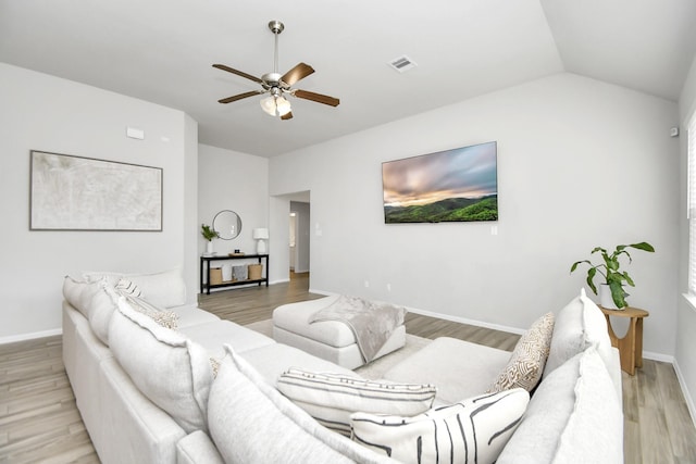 living room with visible vents, light wood-style flooring, vaulted ceiling, ceiling fan, and baseboards