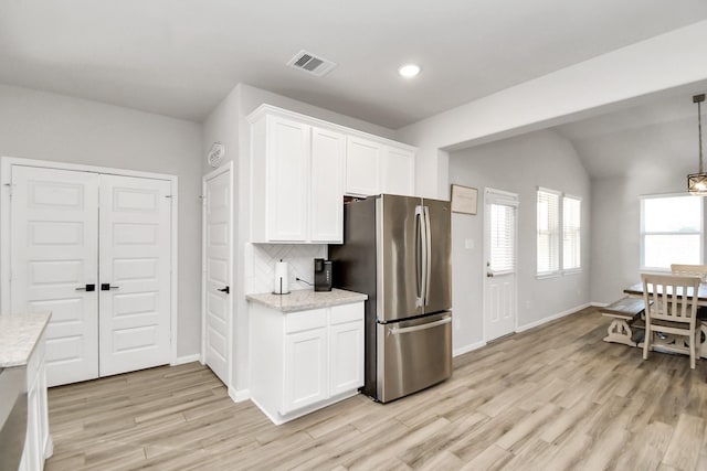 kitchen with visible vents, backsplash, light wood-style floors, freestanding refrigerator, and white cabinetry