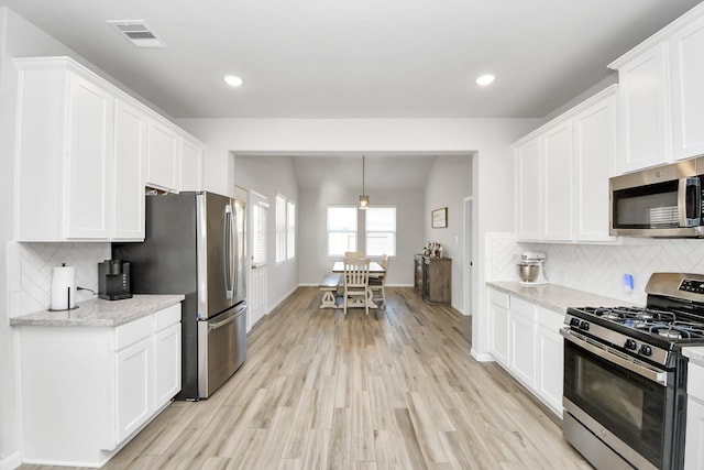 kitchen with visible vents, white cabinets, appliances with stainless steel finishes, light wood-type flooring, and decorative backsplash