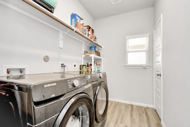 clothes washing area with laundry area, light wood finished floors, washing machine and dryer, and baseboards