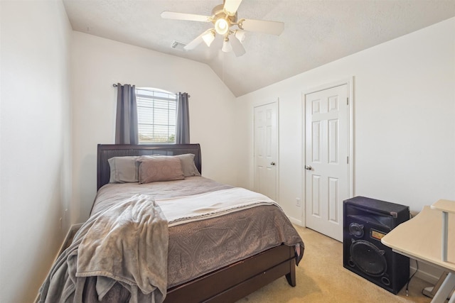 bedroom with ceiling fan, vaulted ceiling, a textured ceiling, and light colored carpet