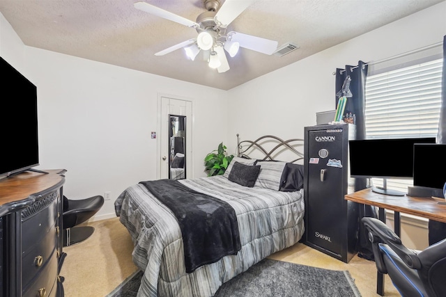 bedroom with light carpet, ceiling fan, visible vents, and a textured ceiling