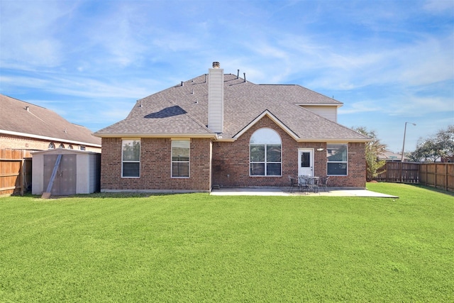 back of house with a storage shed, a fenced backyard, roof with shingles, an outdoor structure, and a patio area