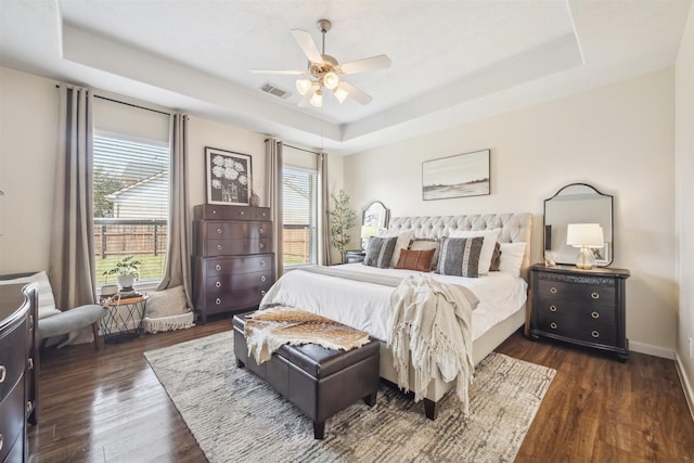 bedroom featuring a raised ceiling, visible vents, dark wood finished floors, and baseboards