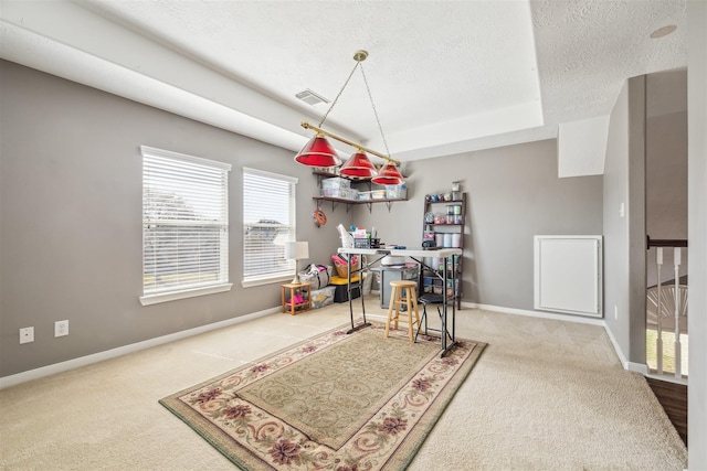 dining space with a textured ceiling, carpet floors, visible vents, baseboards, and a raised ceiling