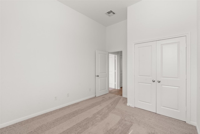 unfurnished bedroom featuring baseboards, a closet, visible vents, and light colored carpet