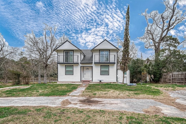 view of front of property with a front yard, fence, and a balcony