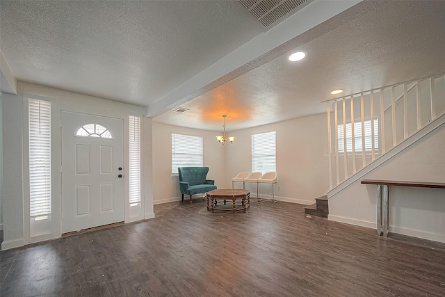 foyer entrance with visible vents, a textured ceiling, stairway, and wood finished floors