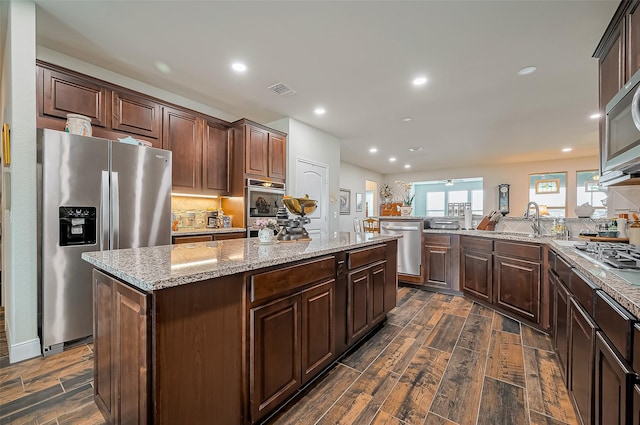 kitchen featuring appliances with stainless steel finishes, a kitchen island, a sink, and wood tiled floor