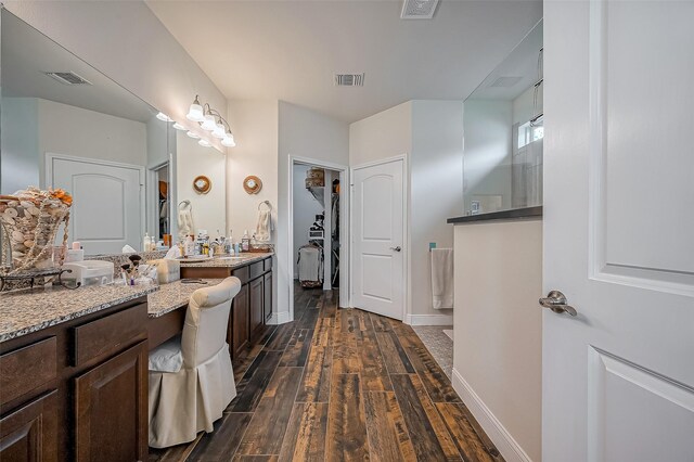 full bath featuring vanity, wood finished floors, visible vents, and a walk in closet