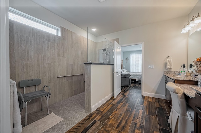 ensuite bathroom with baseboards, connected bathroom, wood finished floors, vanity, and a walk in shower