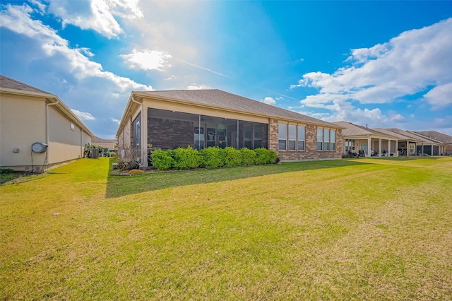 back of property with a yard and brick siding