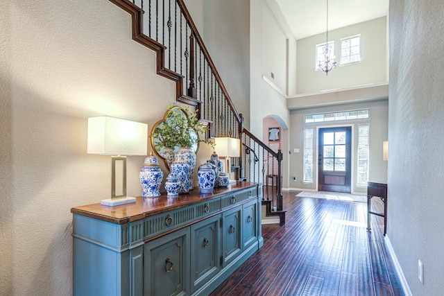 foyer featuring dark wood-style flooring, plenty of natural light, stairway, and baseboards