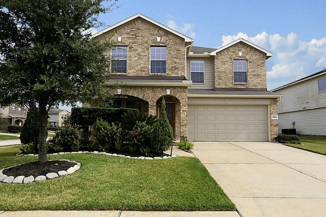 traditional-style house with an attached garage, driveway, brick siding, and a front yard