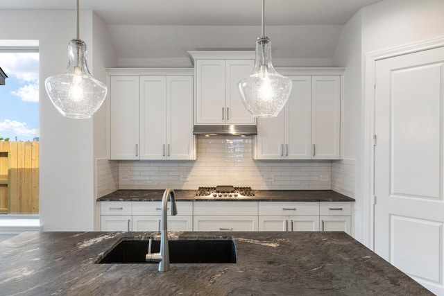 kitchen with under cabinet range hood, a sink, backsplash, white cabinetry, and stainless steel gas stovetop