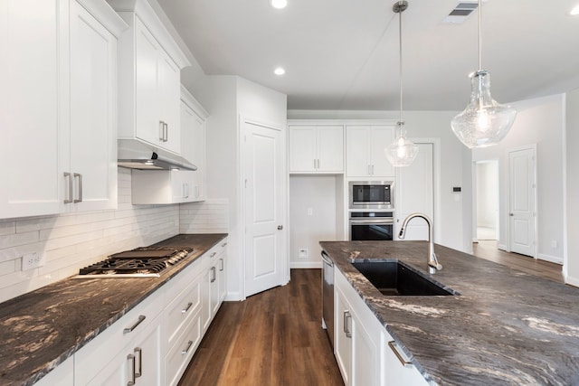 kitchen featuring visible vents, stainless steel appliances, decorative backsplash, dark wood-type flooring, and a sink