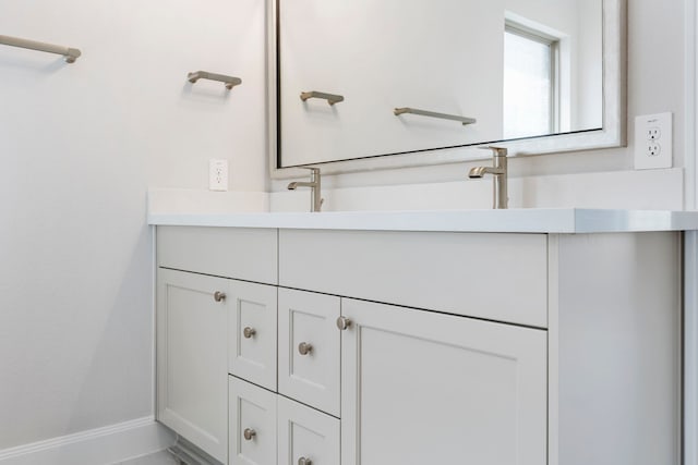 bathroom with double vanity, baseboards, and a sink