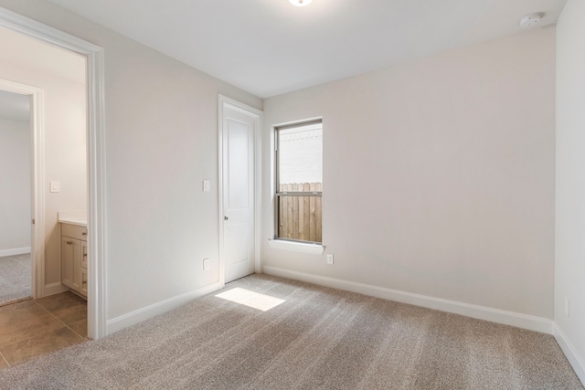 unfurnished bedroom with baseboards, carpet floors, and connected bathroom