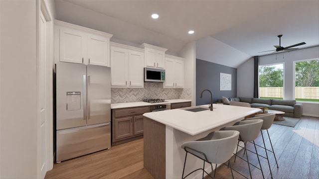 kitchen featuring open floor plan, appliances with stainless steel finishes, light wood-style flooring, and a sink