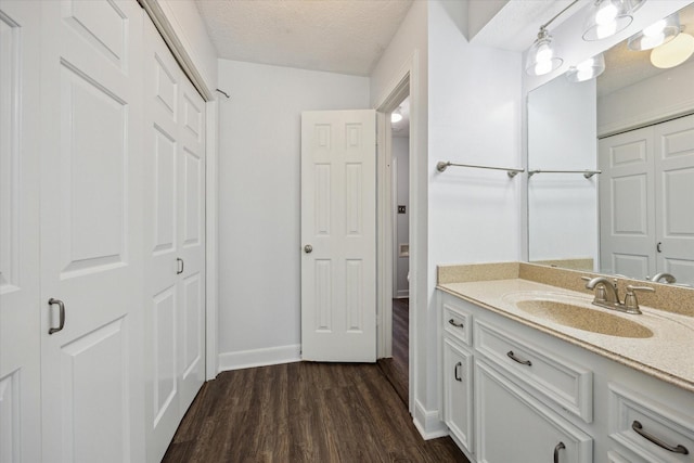 bathroom with a closet, vanity, a textured ceiling, and wood finished floors