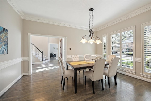 dining room with dark wood-type flooring, ornamental molding, a chandelier, baseboards, and stairs