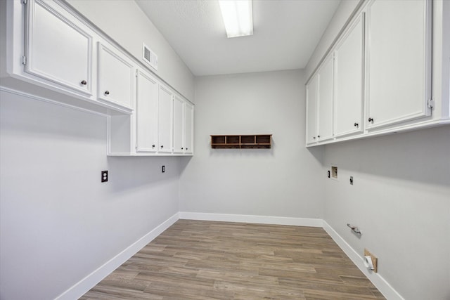 laundry room featuring gas dryer hookup, cabinet space, visible vents, and baseboards