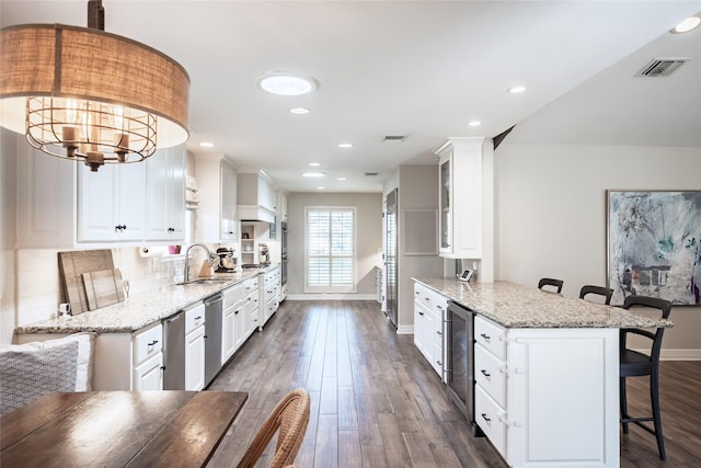 kitchen featuring wine cooler, a breakfast bar area, a sink, visible vents, and stainless steel dishwasher