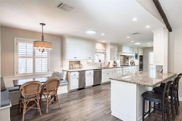 kitchen with appliances with stainless steel finishes, visible vents, dark wood-type flooring, and a sink