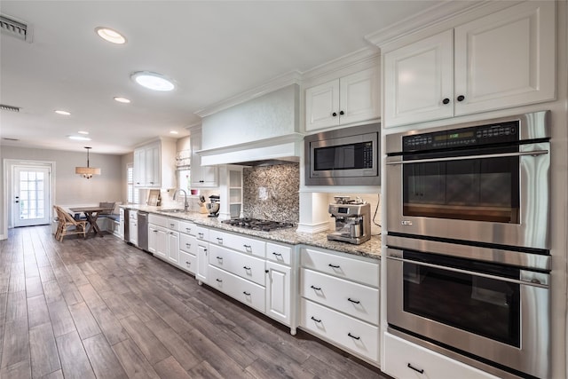 kitchen with visible vents, dark wood finished floors, stainless steel appliances, white cabinetry, and a sink