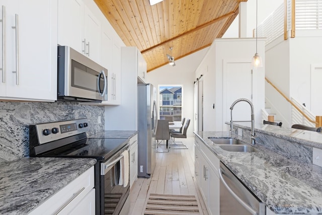 kitchen featuring a barn door, wooden ceiling, appliances with stainless steel finishes, a sink, and backsplash