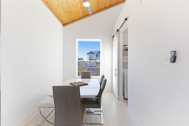 dining area with washer / dryer, a barn door, lofted ceiling, wood ceiling, and light wood-style floors