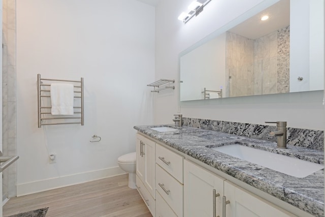 bathroom featuring a tile shower, wood finished floors, a sink, and radiator